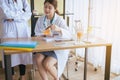 Doctor beautiful asian woman sitting and working on desk using foot fingers plastic anatomy physiology model a bone and hand point Royalty Free Stock Photo