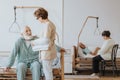 Doctor in a beige uniform talks to an elderly patient during a walk around hospital