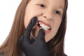 A doctor in black medical gloves examines the oral cavity of a little cute girl. Crooked teeth. Studio photo on a white background