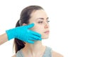 A doctor in a blue glove touches the cheek of a young girl without makeup that looks toward close-up Royalty Free Stock Photo