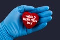 Doctor in blue gloves holds a heart with text World hepatitis day, concept