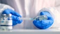 Doctor in blue latex gloves fill in syringe with medicine from glass vial for injection of an elderly person in a medical Royalty Free Stock Photo