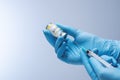 Doctor in blue latex gloves fill in syringe with vaccine from glass vial. Royalty Free Stock Photo