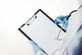 Doctor in blue latex gloves holding medical clipboard with empty blank sheet of paper.Empty clipboard template Royalty Free Stock Photo