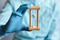 A doctor in blue medical gloves holds an hourglass - a symbol of time to heal and cure