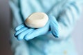 A doctor in blue medical gloves holds a white little - a symbol of protection against disease, coronovirus COVID-19