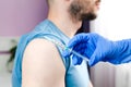 A doctor in blue rubber protective gloves makes an injection or vaccination to male patient. Health care. Covid-19 vaccination. Royalty Free Stock Photo