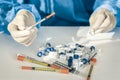 Doctor in a blue surgical gown and mask holds in his hand a medical syringe and bottle with insulin for diabetes. Many syringes