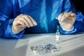 Doctor in a blue surgical gown and mask holds in his hand a medical syringe and bottle with insulin for diabetes. Many syringes