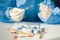 Doctor in a blue surgical gown and mask holds in his hand a medical syringe and bottle with insulin for diabetes. Many syringes