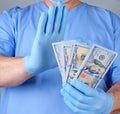 Doctor in blue uniform and datex gloves holds a lot of paper money Royalty Free Stock Photo