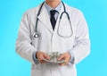 Doctor with bribe on light blue background. Corruption in medicine Royalty Free Stock Photo