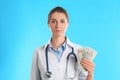 Doctor with bribe money on blue background. Corruption in medicine Royalty Free Stock Photo