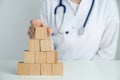 Doctor building pyramid of blank wooden cubes on white table against light background, closeup. Space for text Royalty Free Stock Photo