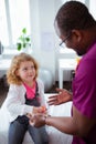 Dark-skinned doctor giving candies to cute little girl