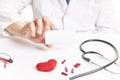 Doctor with a card with pills, a stethoscope and a red heart