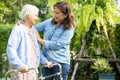 Doctor caregiver help and care Asian senior woman patient walk with walker in park at hospital Royalty Free Stock Photo