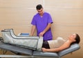 Doctor checking legs pressotherapy machine on woman