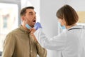 doctor checking male patient's throat at hospital