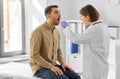 doctor checking male patient's throat at hospital