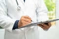 Doctor checking and note diagnosis medicine in clipboard of patient in hospital