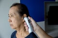 Doctor checking patient`s temperature in the ear with Tympanic Thermometer, inside the hospital or clinic. Royalty Free Stock Photo