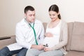 Doctor is checking pregnant woman`s belly with a stethoscope. Physician is listening to a heartbeat of a baby