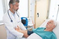 Doctor checking senior mans blood pressure in hospital Royalty Free Stock Photo