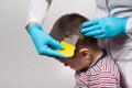 The doctor checks the presence of lice in a small child with the help of a crest. Pediculosis in kindergarten, preventive