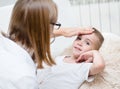 Doctor checks the temperature of a boy touching his forehead