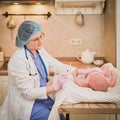 Doctor checks the temperature of the newborn baby with a thermometer. A nurse in uniform measures the child fever with a Royalty Free Stock Photo