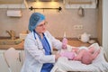 Doctor checks the temperature of the newborn baby with a thermometer. A nurse in uniform measures the child fever with a Royalty Free Stock Photo