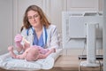 Doctor checks the throat of a newborn child with a plowshare. A nurse in uniform with a wooden stick in her hand examines the Royalty Free Stock Photo