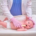 Doctor checks the throat of a newborn child with a plowshare. A nurse in uniform with a wooden stick in her hand examines the Royalty Free Stock Photo