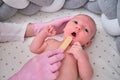 Doctor checks the throat of a newborn child with a plowshare. A nurse in uniform with a wooden stick in her hand examines the Royalty Free Stock Photo