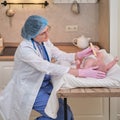 Doctor checks the throat of a newborn child with a plowshare. A nurse in uniform with a wooden stick in her hand examines the Royalty Free Stock Photo