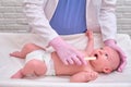 Doctor checks the throat of a newborn child with a plowshare. A nurse in uniform with a wooden stick in her hand examines the Royalty Free Stock Photo