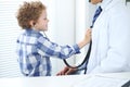 Doctor and child patient. Little boy play with stethoscope while physician communicate with him. Children`s therapy and