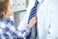 Doctor and child patient. Little boy play with stethoscope while physician communicate with him. Children`s therapy and