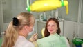 The doctor of the clinic tells the teenager about the treatment of oral cavity