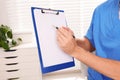 Doctor with clipboard in clinic, closeup. Patient consultation