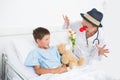 Doctor in clown costume entertaining ill boy in hospital Royalty Free Stock Photo