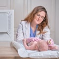 The doctor is combing the hair of a newborn baby. Nurse in uniform with a comb in hand for a child