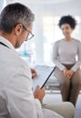 Doctor, consultation and writing on clipboard with patient in hospital office for symptoms, records or notes. Healthcare Royalty Free Stock Photo