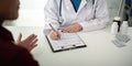Doctor consulting male elderly patient filling medical form. Professional physician writing information in clipboard Royalty Free Stock Photo
