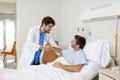 Doctor consulting patient lying on hospital bed being released shaking hands in modern clinic