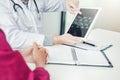 Doctor consulting with patient presenting x-ray film results on digital tablet tablet sitting at table Royalty Free Stock Photo