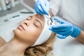 Doctor cosmetologist applies a transparent moisturizing mask to a woman`s face. Face skin preparation for the ultrasonic