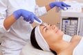 The doctor-cosmetologist makes the apparatus a procedure of ultrasound cleaning of the facial skin of a beautiful, young woman in Royalty Free Stock Photo