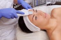The doctor-cosmetologist makes the apparatus a procedure of ultrasound cleaning of the facial skin of a beautiful, young woman in Royalty Free Stock Photo